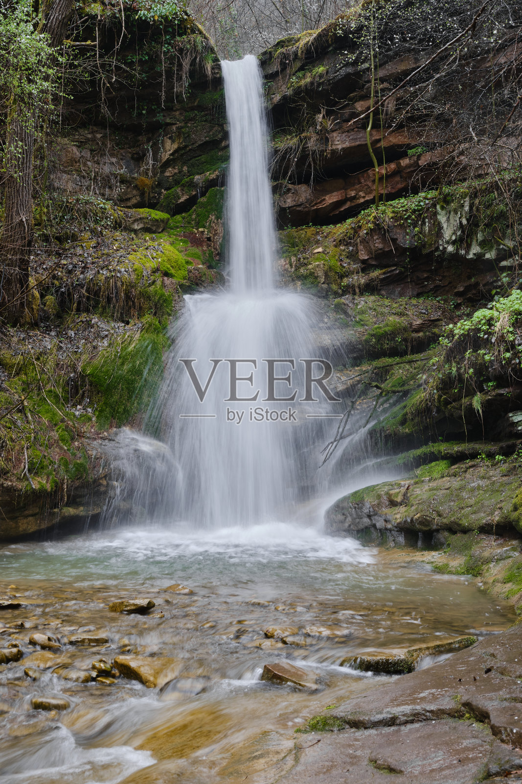 可爱，小，但强大的瀑布在春天，与红色的岩石，绿色的苔藓和新鲜的植物照片摄影图片