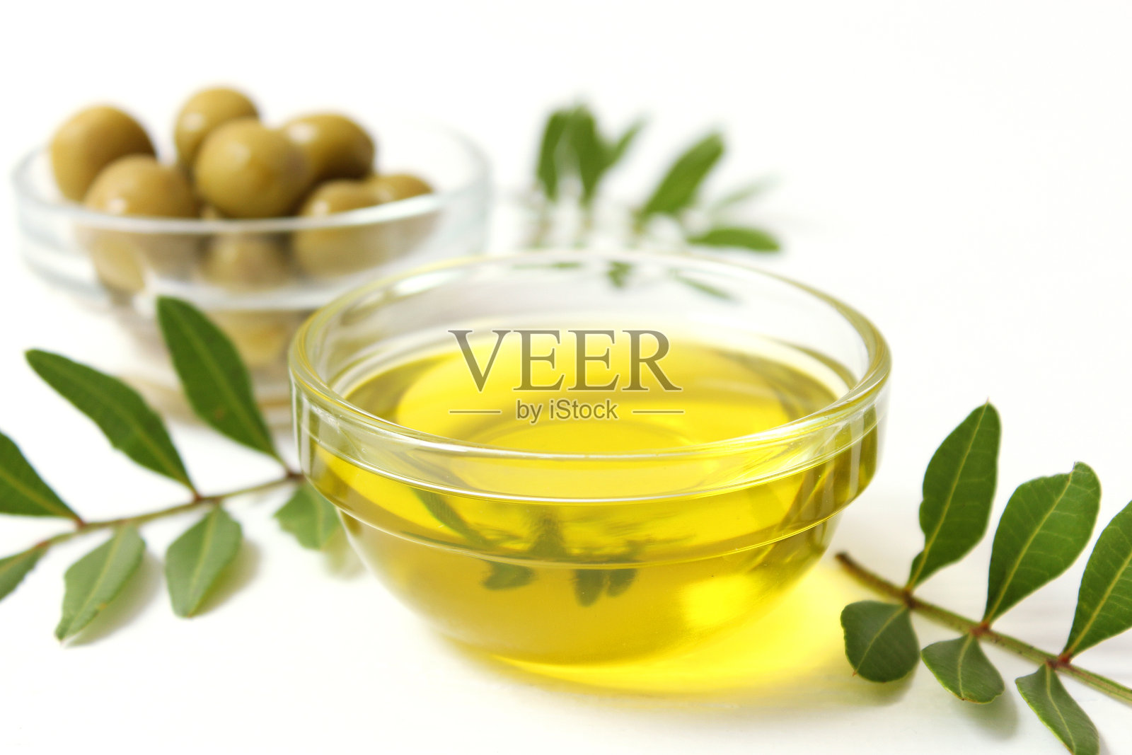 桌上有橄榄油、绿叶和橄榄。照片摄影图片