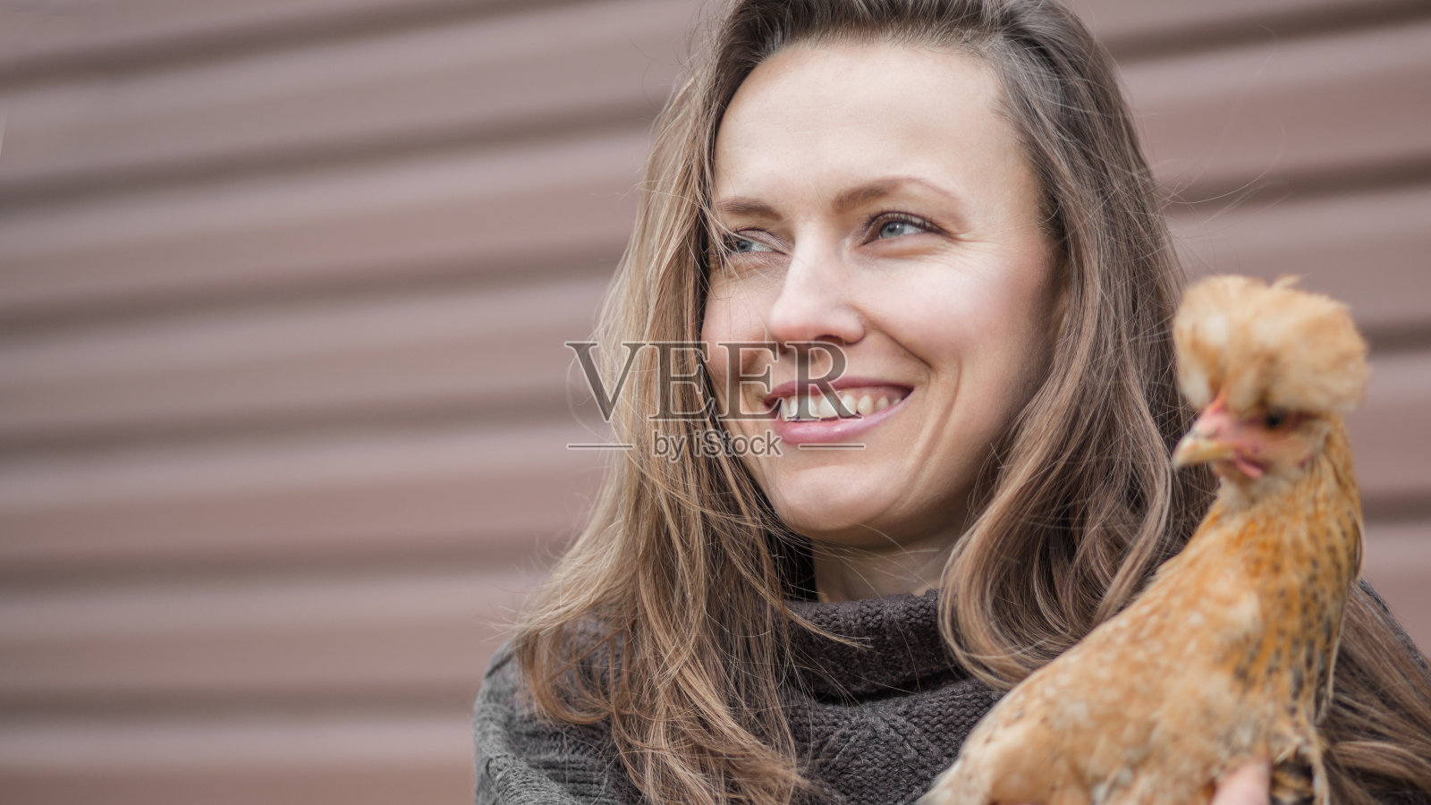 快乐的年轻女人和一只棕色母鸡照片摄影图片