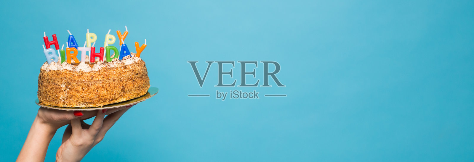 双手捧着生日蛋糕，上面插着蜡烛，蓝色背景上刻着生日的字样。本空间照片摄影图片