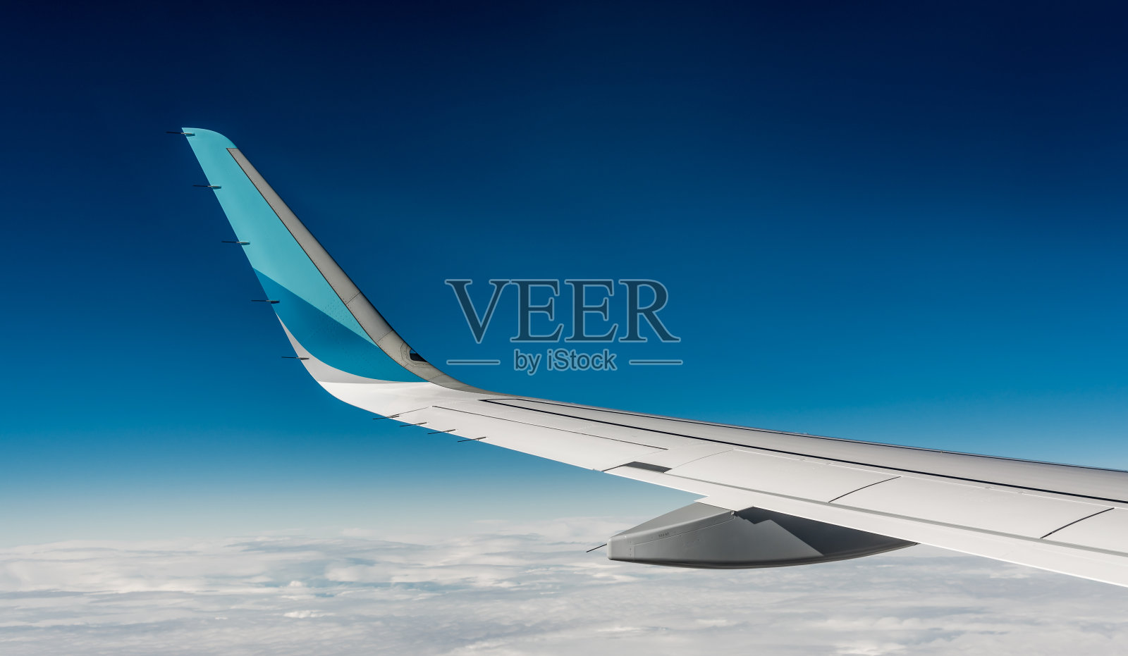 飞机的机翼。在飞机飞行期间从窗口座位观看。蓝色的天空和柔软的白云照片摄影图片