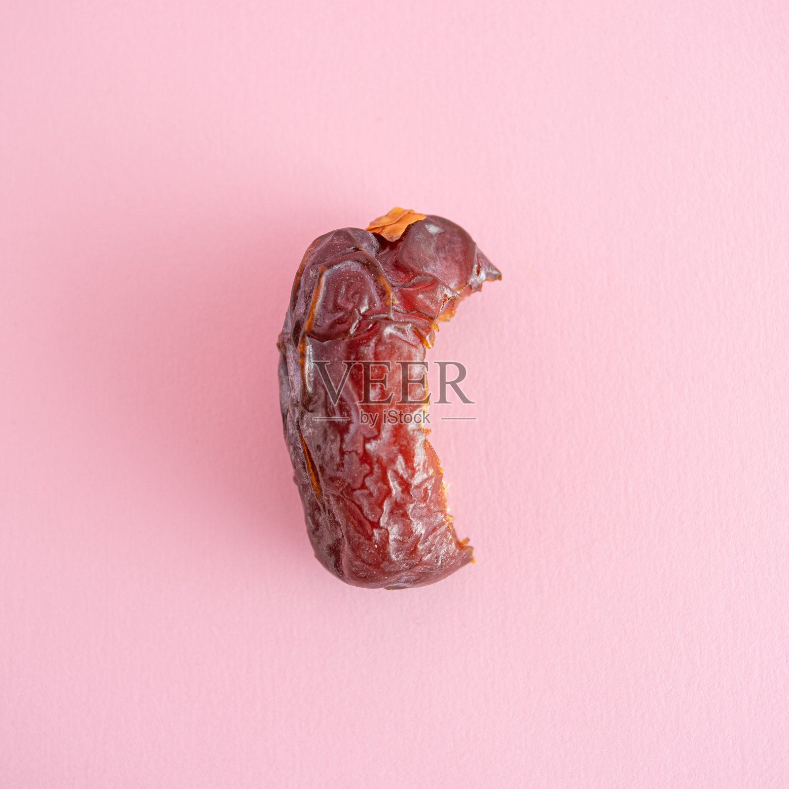 斋月食物的最小概念:干棕色皇家枣吃到一半在充满活力的粉红色背景。平躺，俯视图方形裁切照片。照片摄影图片