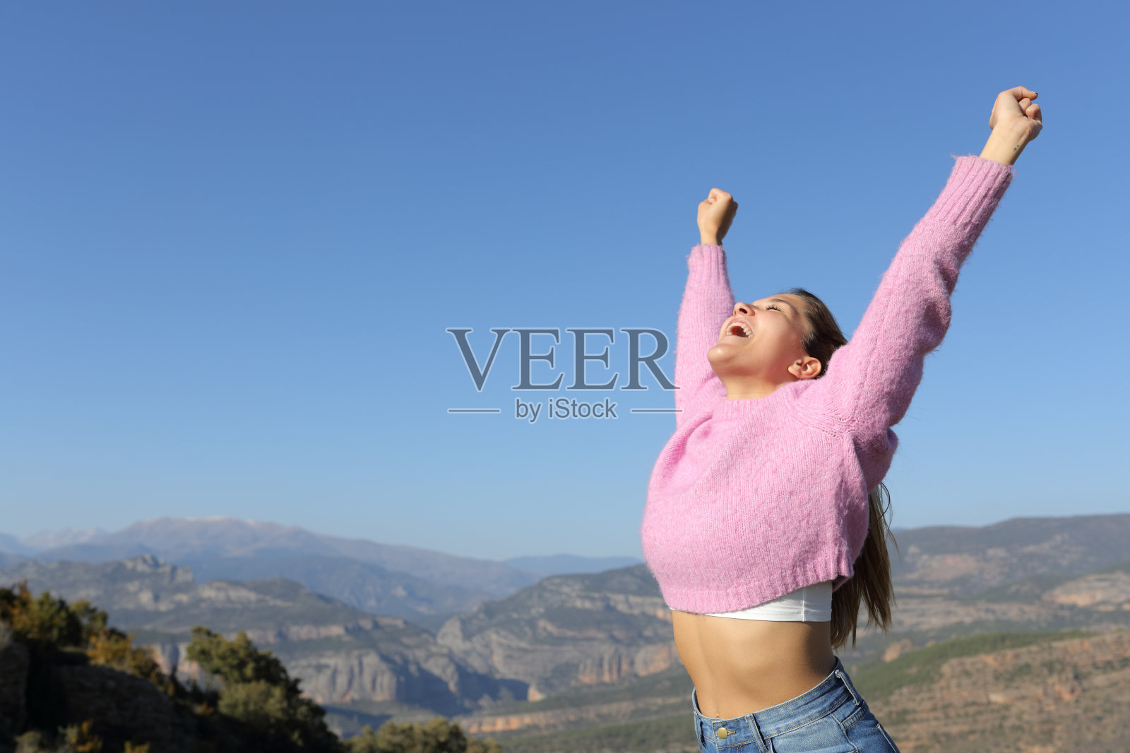 兴奋的女人在山上举起双臂庆祝假期照片摄影图片