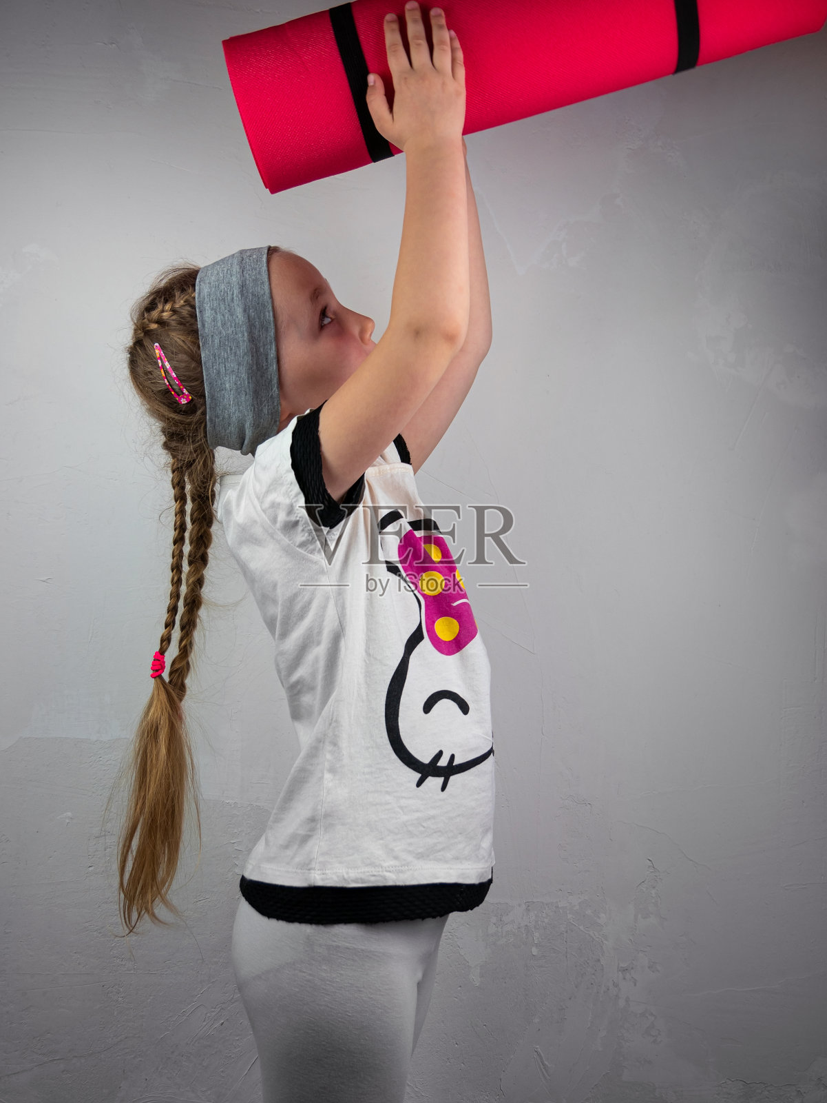 灰色背景下，粉色瑜伽垫的小女孩。瑜伽为儿童心理健康积极的生活方式，运动健身类照片摄影图片