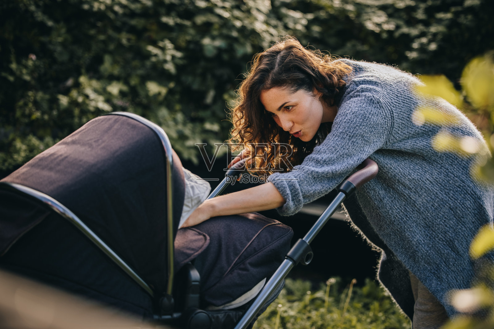 快乐的妈妈和婴儿车里的婴儿玩照片摄影图片