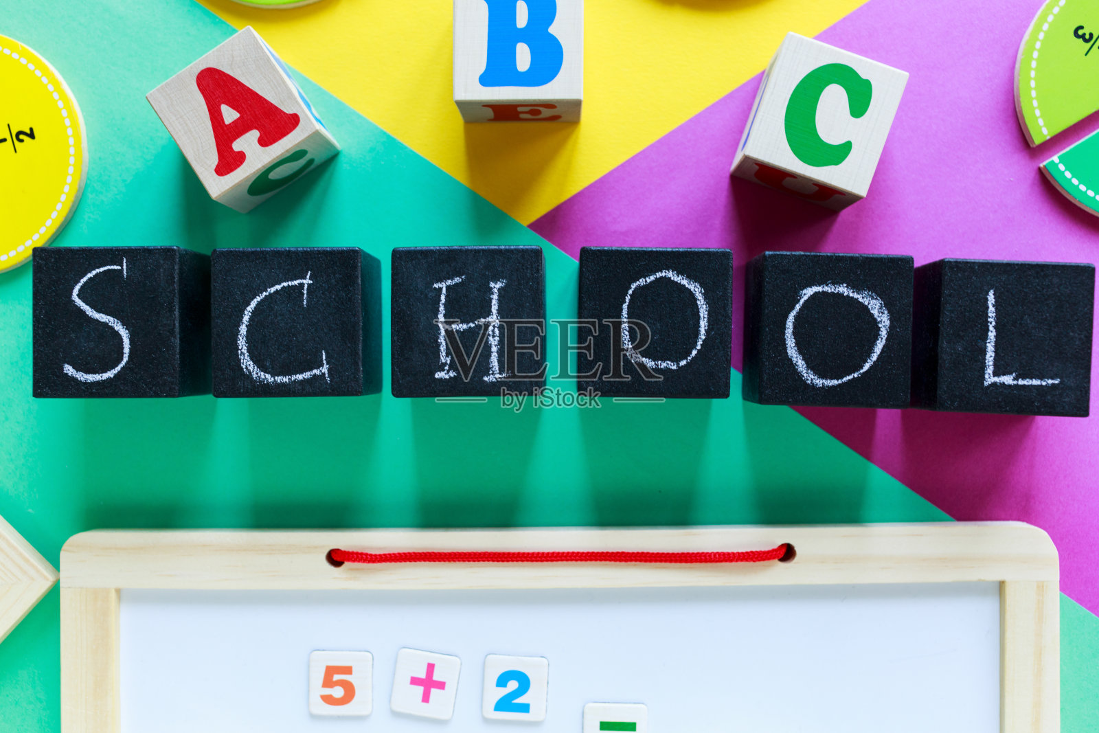 彩色数学分数在绿色，黄色，紫色的背景。桌子上有学校字样的街区。对孩子们来说，有趣的数学。教育，回归学校理念照片摄影图片
