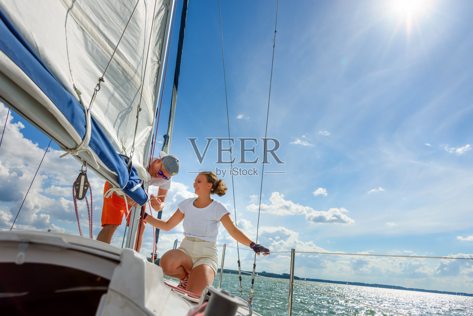 在夏季度假期间，年轻的男子和女子作为帆船船员修剪主帆照片摄影图片