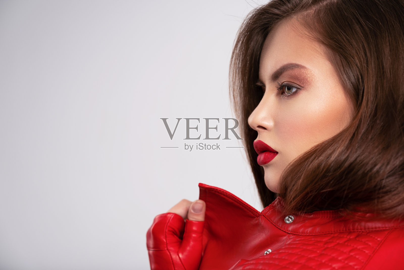 简介肖像美丽的年轻女子与明亮的化妆。漂亮的黑发，唇上涂着鲜红的口红。一头棕色长发的漂亮女孩。穿着黑色皮夹克的黑发女人。照片摄影图片