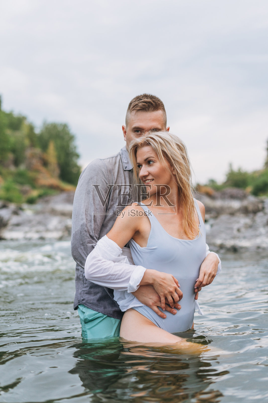 幸福的年轻情侣在相爱的旅行者在山间的河流接吻照片摄影图片