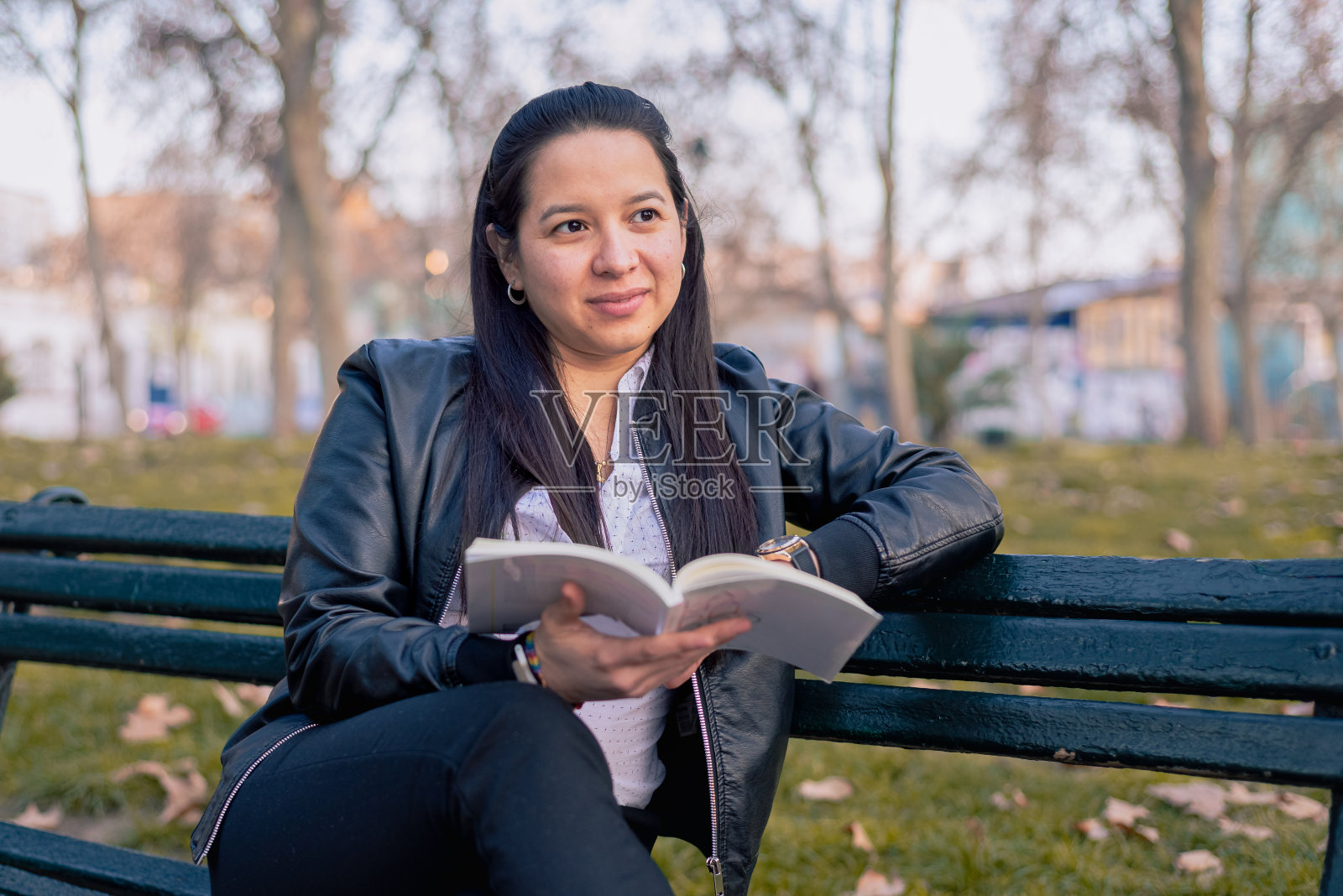 年轻女子在公园里看书坐在公园的一个银行照片摄影图片