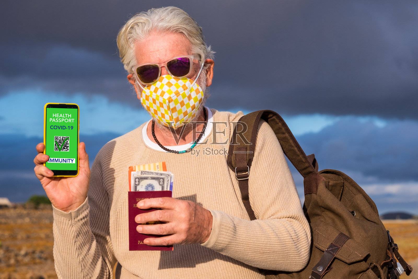 一名戴着防护口罩的老人展示给接种了冠状病毒疫苗的人的健康护照app，准备再次旅行照片摄影图片