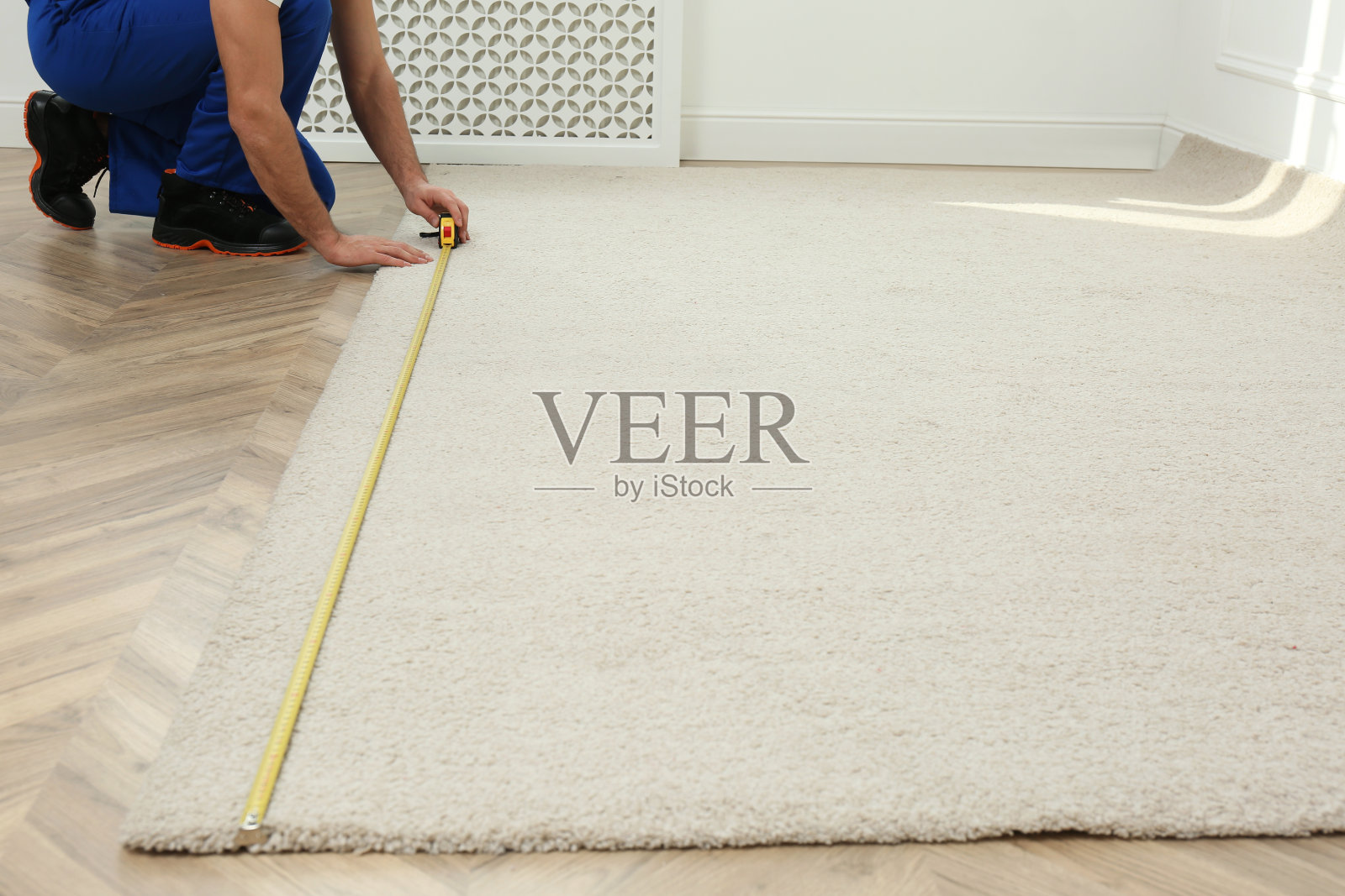 工人用卷尺在室内安装新地毯，特写照片摄影图片