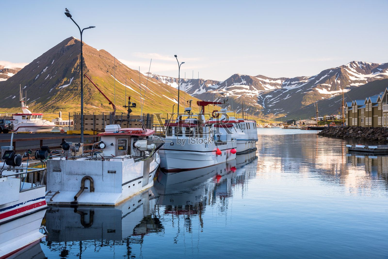 在晴朗的夏日，渔船停泊在峡湾的码头上照片摄影图片