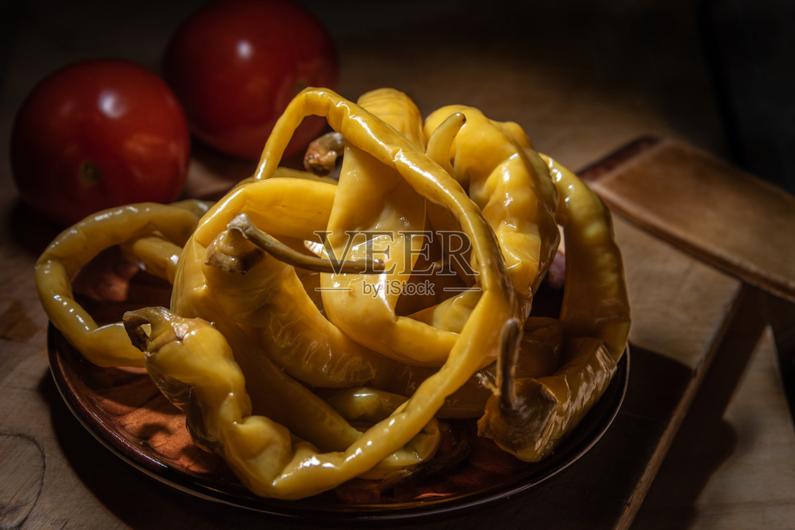 长长的腌辣椒和西红柿放在盘子里照片摄影图片