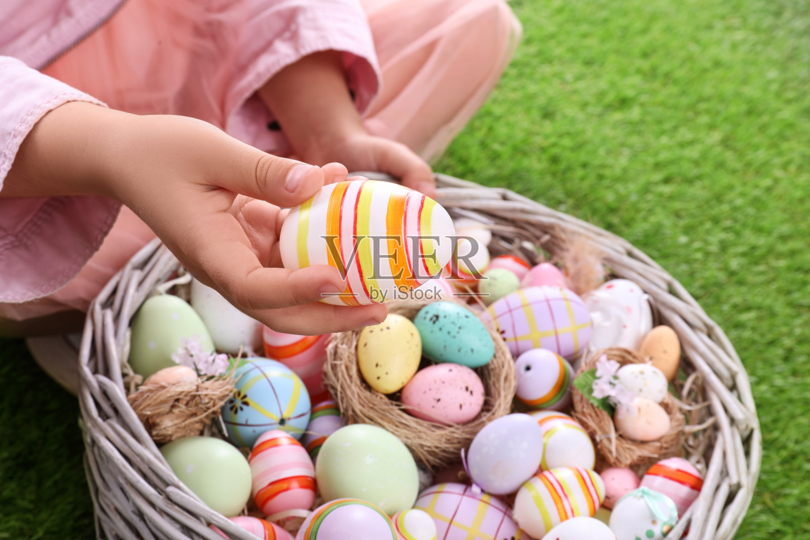 孩子带着装满复活节彩蛋的柳条篮子在绿色的草地上，特写照片摄影图片