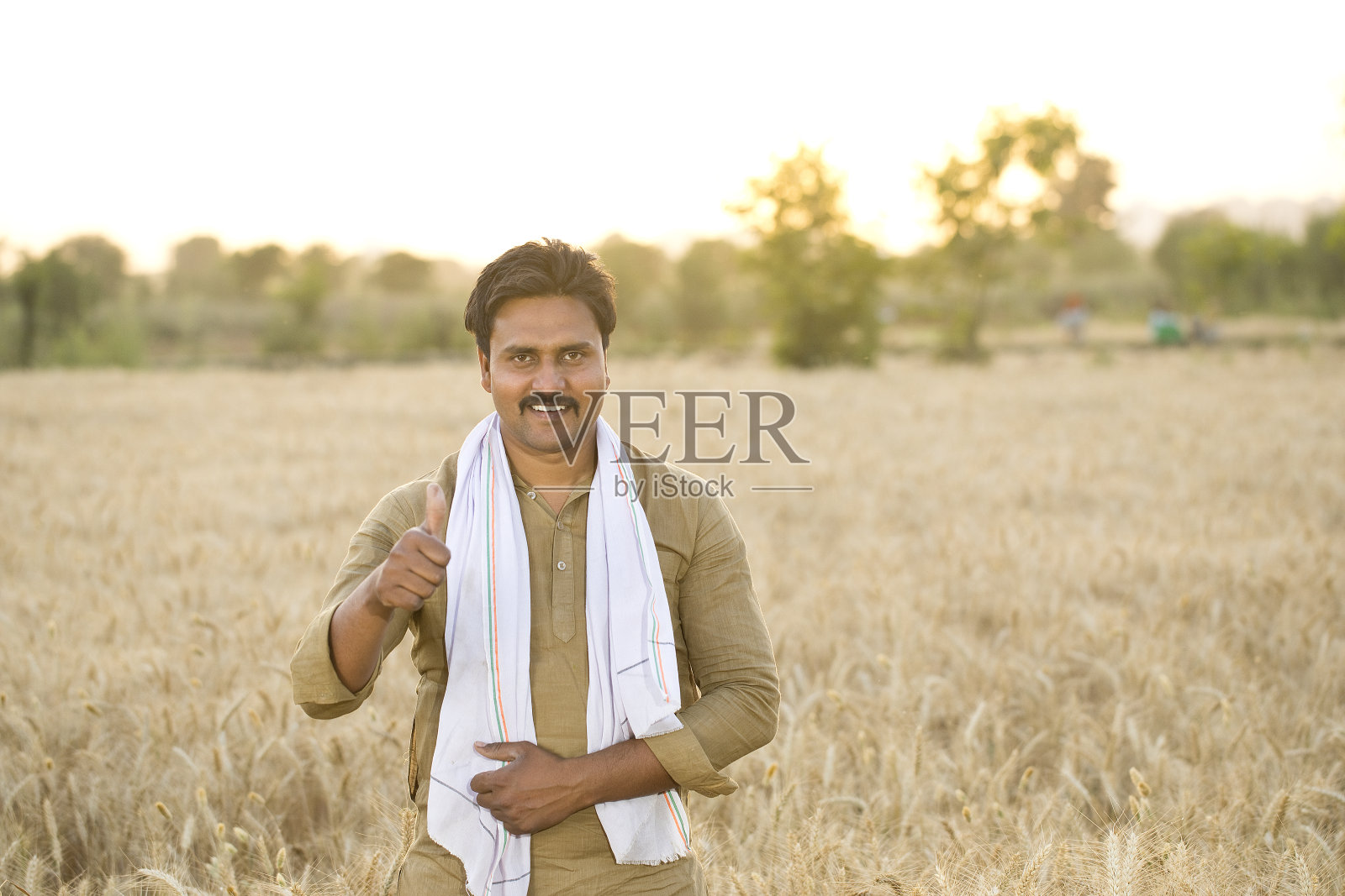 快乐的农民在农田里竖起大拇指照片摄影图片