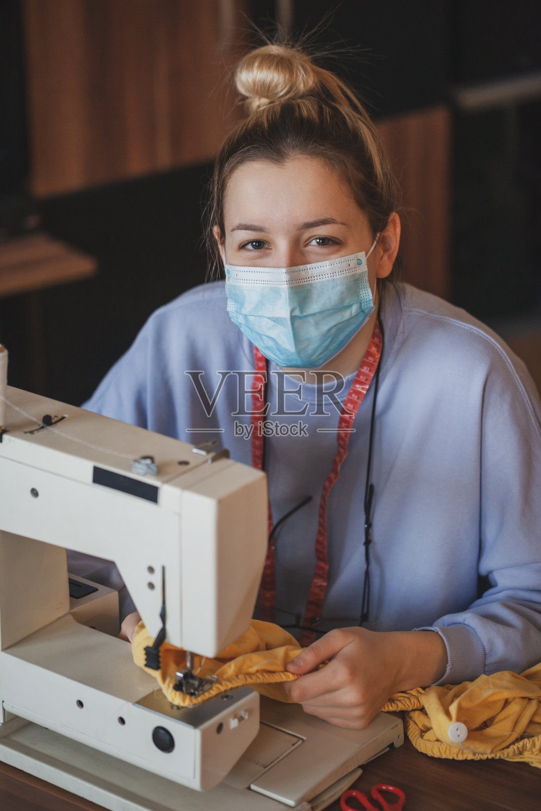 年轻的女裁缝在缝纫机上缝衣服照片摄影图片