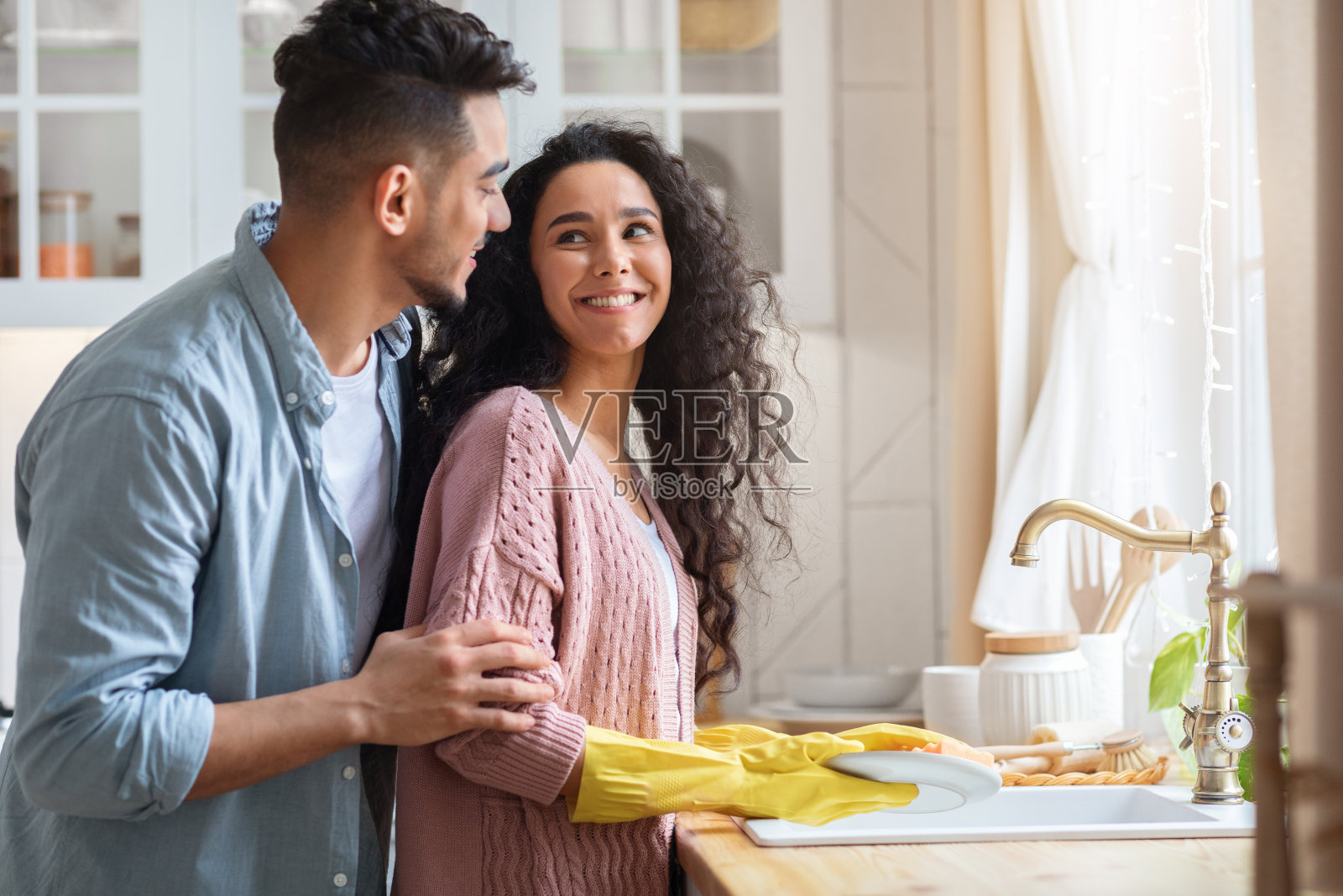 阿拉伯丈夫从背后拥抱正在洗碗的妻子照片摄影图片