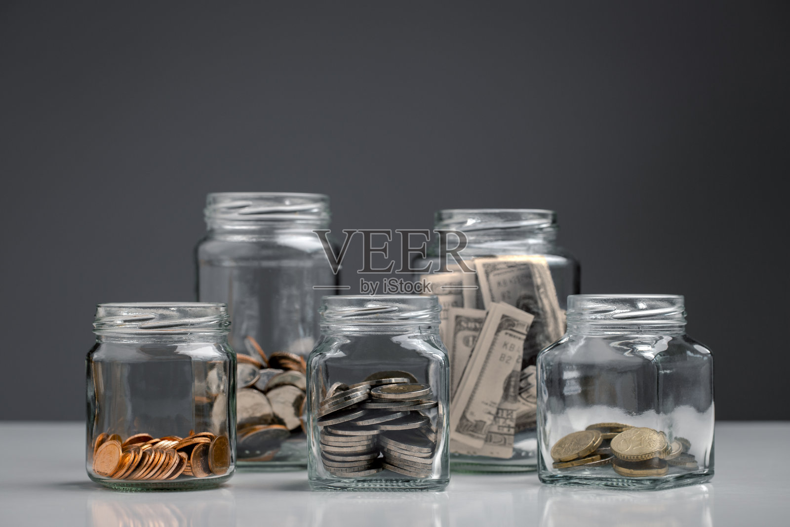 硬币和钞票在一个玻璃罐，金钱管理，个人理财概念。照片摄影图片