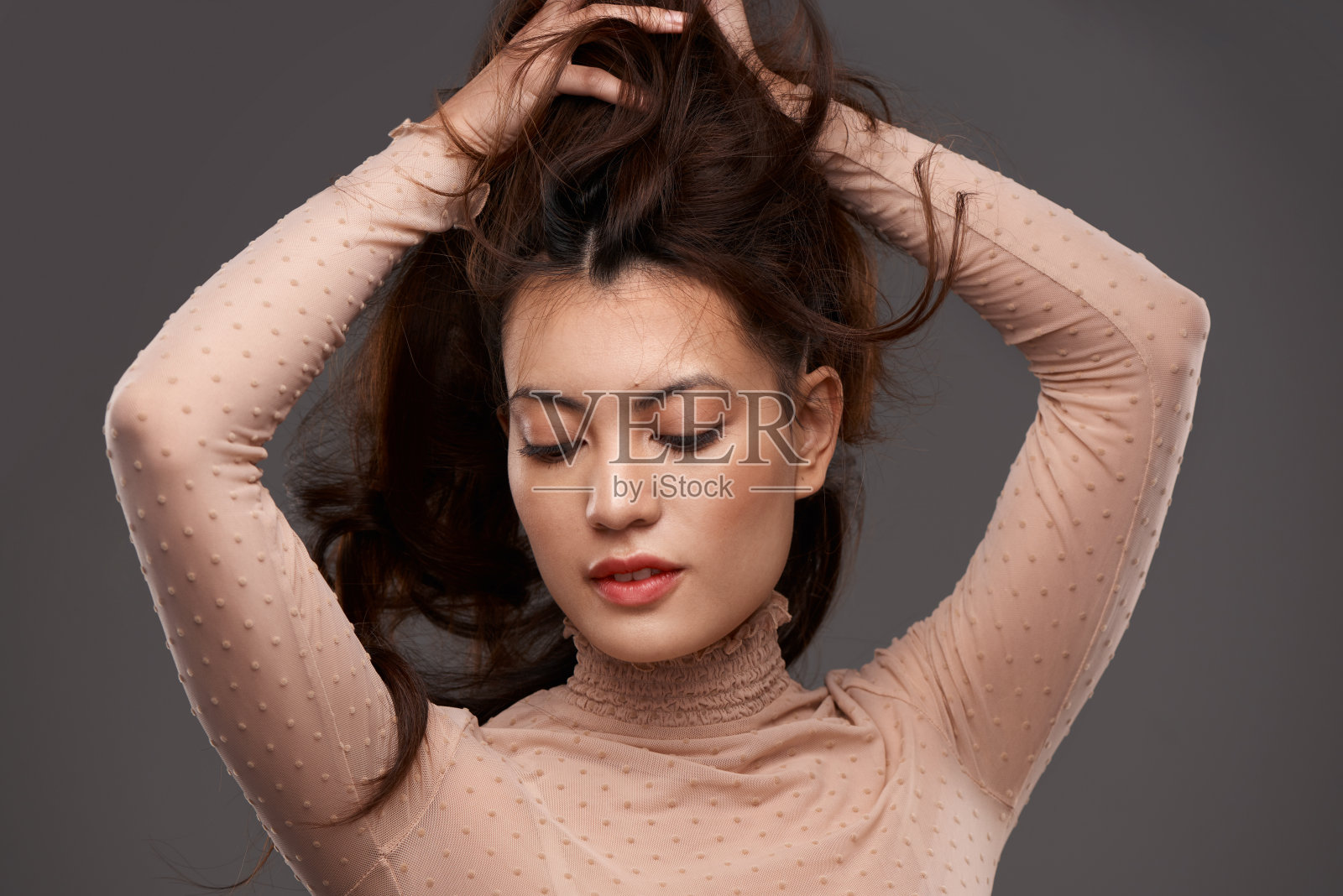 一个迷人的年轻女子在工作室摆姿势，背景是灰色照片摄影图片