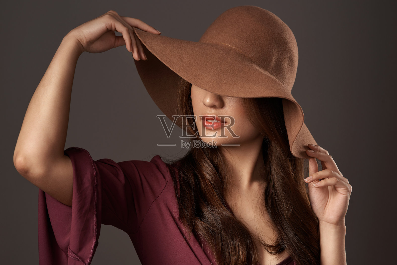 一个迷人的年轻女子在工作室摆姿势，背景是灰色照片摄影图片