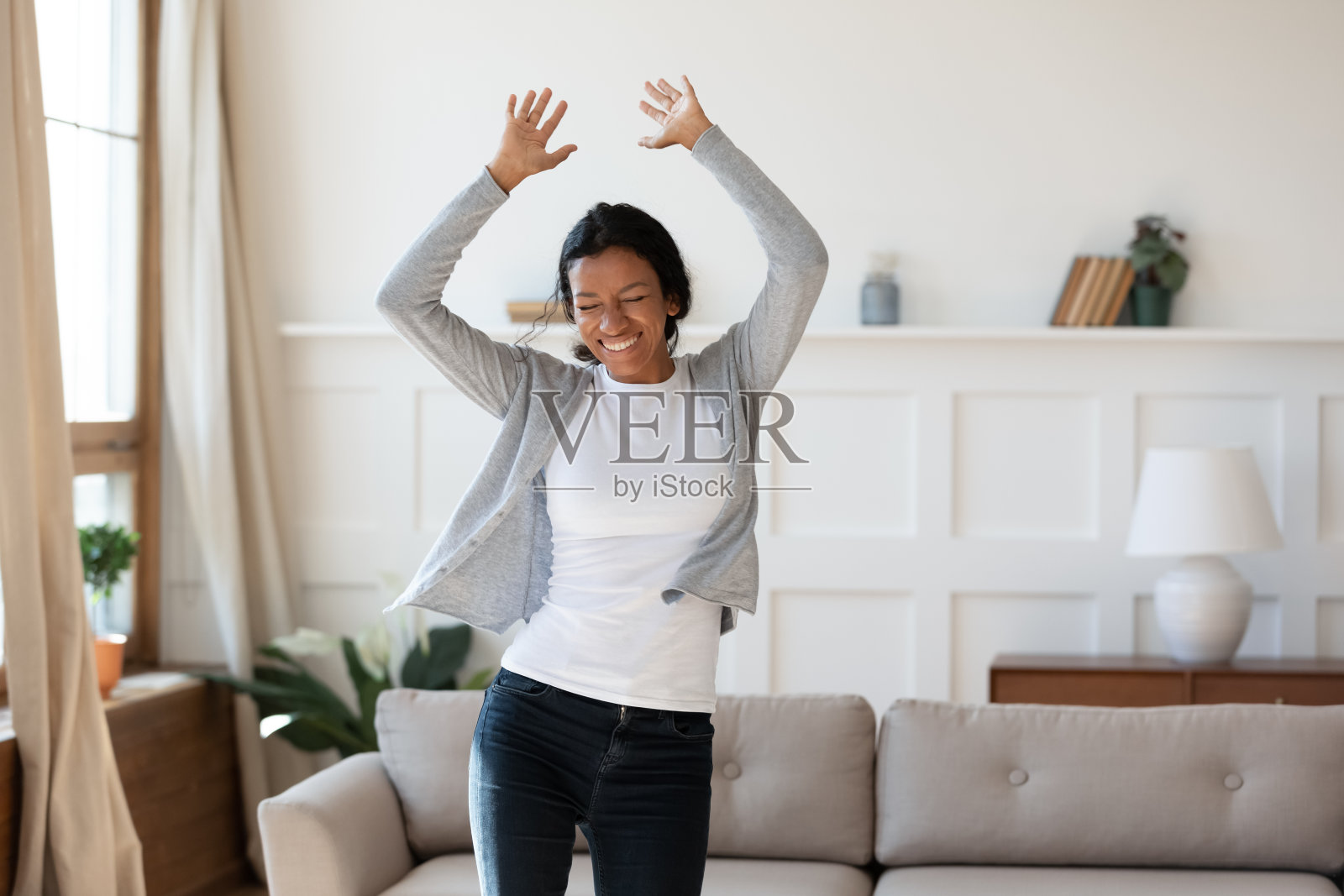 年轻的非洲裔美国妇女在家里跳舞。照片摄影图片