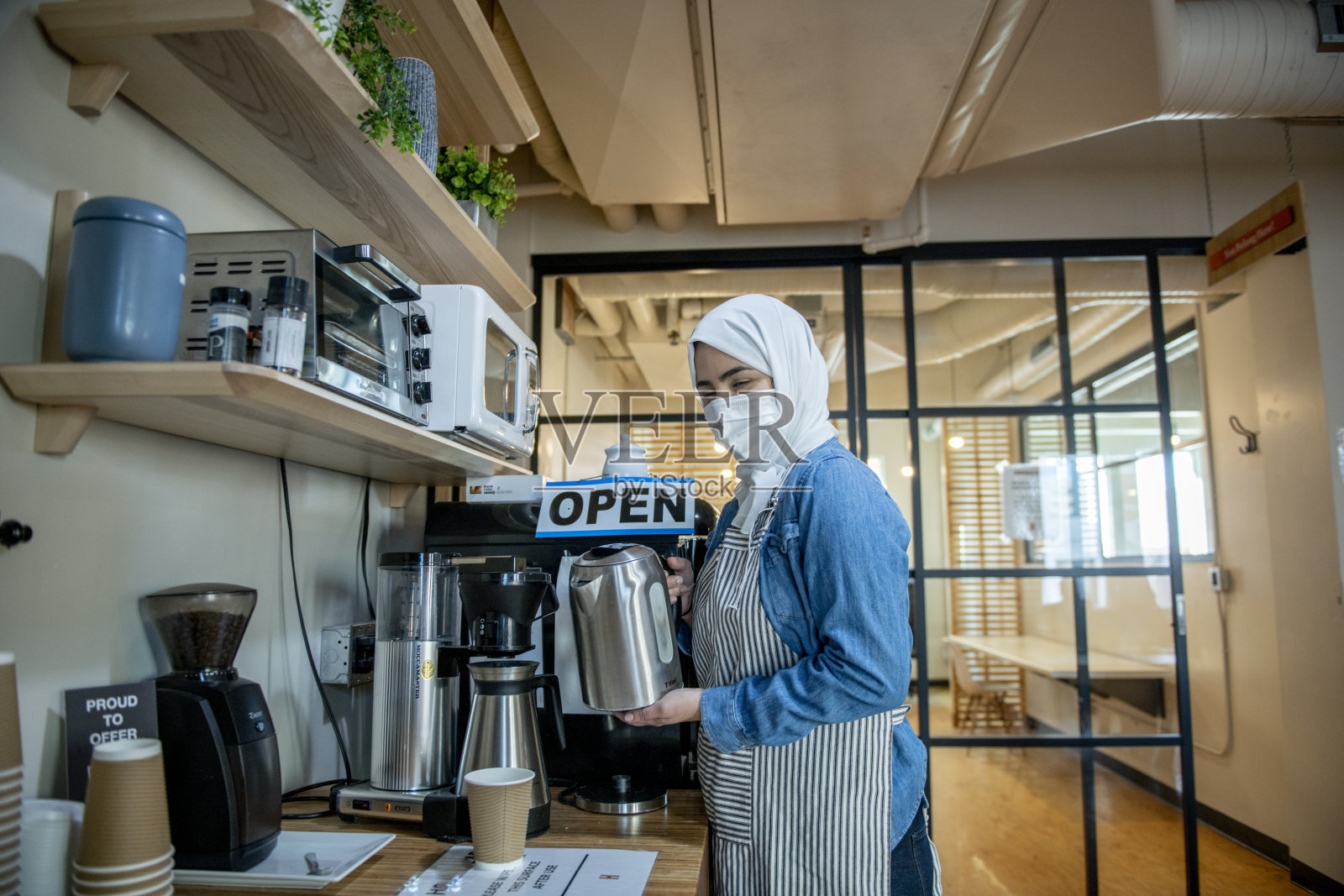 在咖啡馆里准备咖啡的穆斯林女店主照片摄影图片