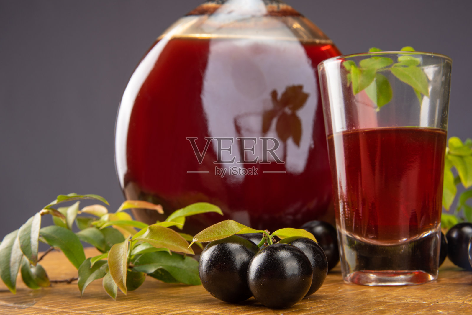 Jaboticaba，瓶和杯自制巴西Jaboticaba利口酒在木材上与树叶和树枝，也Jaboticaba构成的场景，光背景，选择性焦点。照片摄影图片