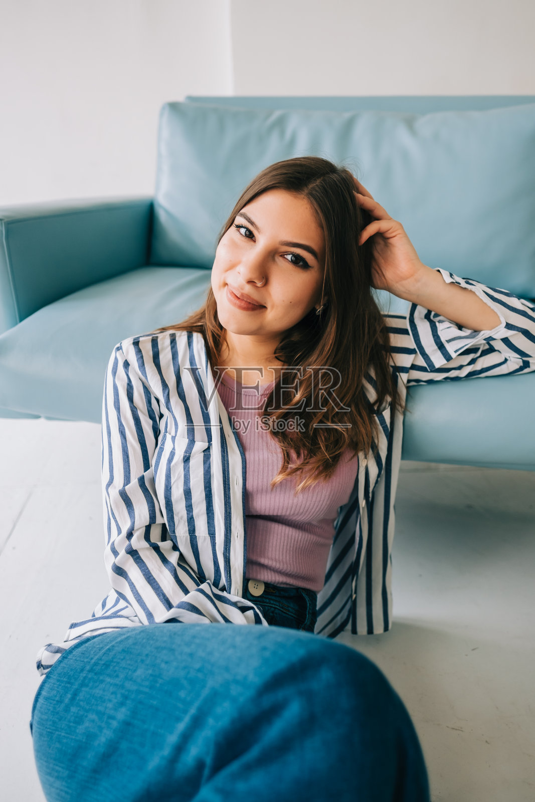 年轻冷静的白种女人放松，坐在现代客厅沙发附近的地板上，慵懒快乐的女人休息在家里……照片摄影图片