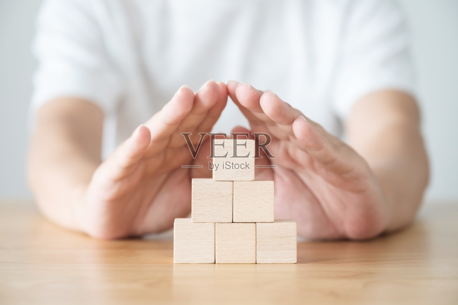 一个男人的手保护木桌上的木块组照片摄影图片