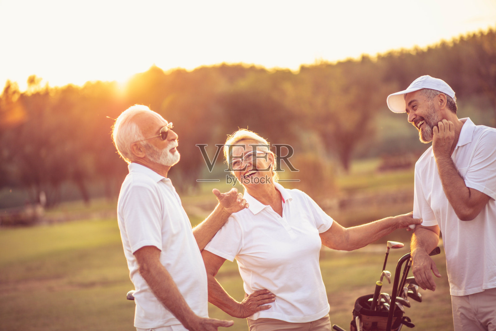 三个老高尔夫球手在高尔夫球场上交谈。照片摄影图片
