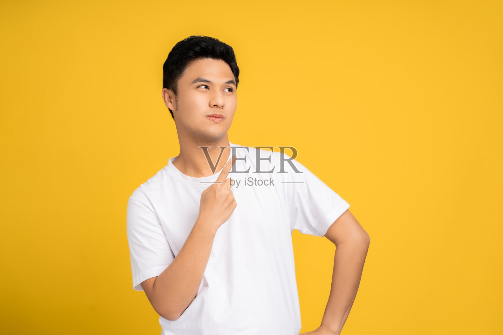 快乐的年轻亚洲人指着他的手指在黄色的背景上的顶部。照片摄影图片