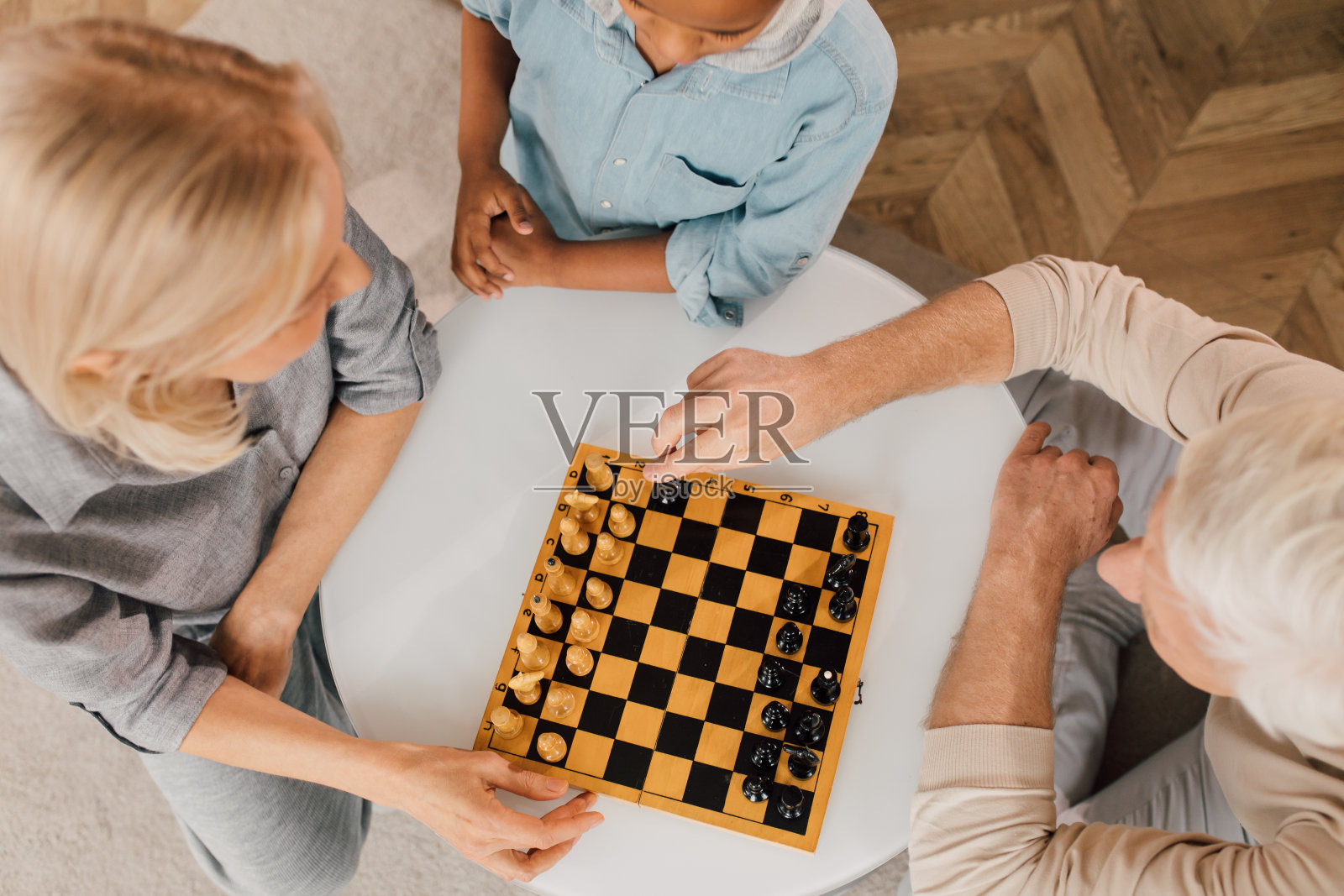 父亲，他的妻子和他们聪明的儿子一起下棋照片摄影图片