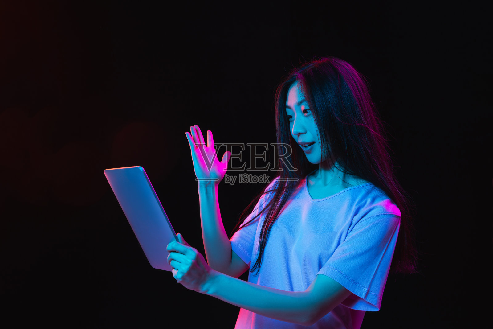 亚洲年轻女子的肖像在黑暗的工作室背景霓虹灯。人的情感、面部表情、青春、销售、广告的概念。照片摄影图片