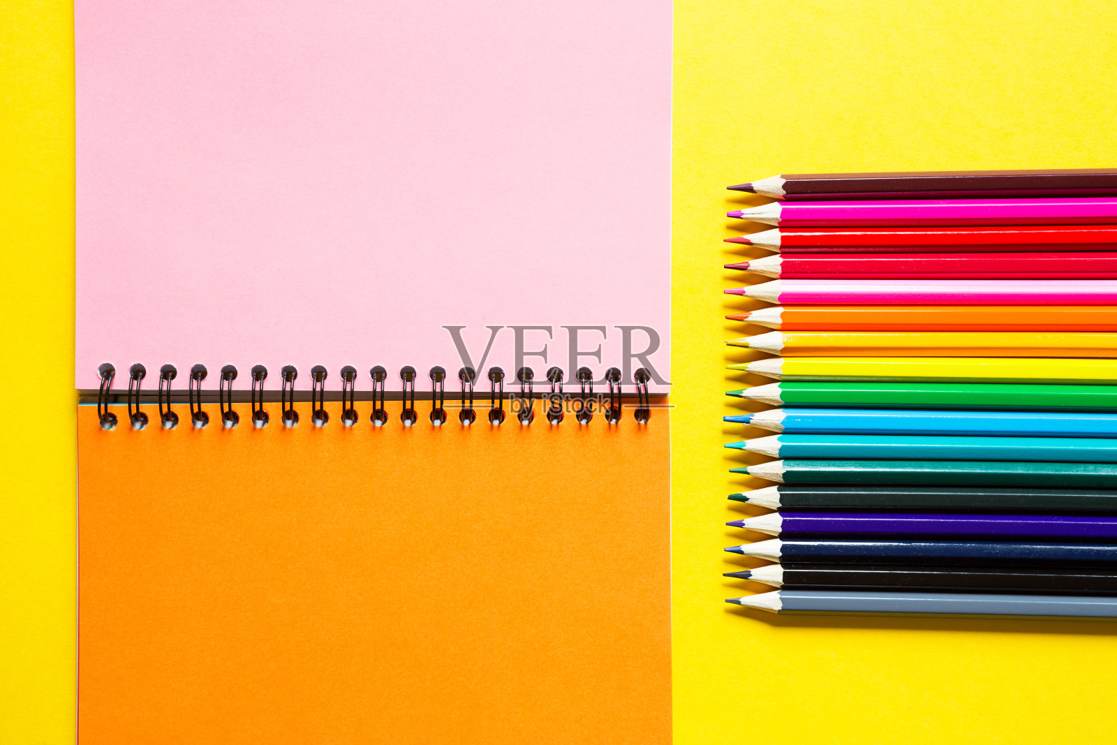 彩虹色调色板的彩色铅笔与螺旋笔记本上的黄色背景，模拟，平躺。回到学校，招生，艺术家，绘画课。副本的空间。文具的创造力照片摄影图片