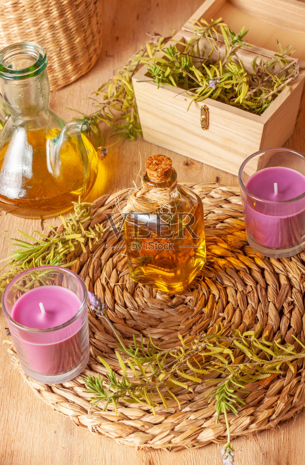 这是一幅静物画，画中是一罐薰衣草油，两根薰衣草香薰蜡烛放在一个西班牙三脚架上，还有一个木盒子，里面有薰衣草花枝。照片摄影图片