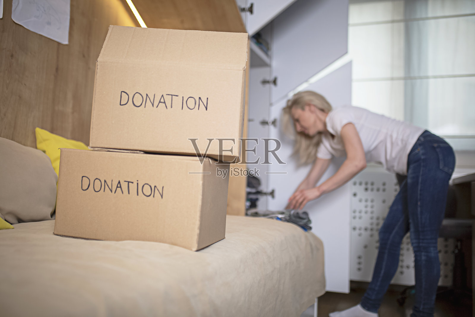 一名妇女正从儿子的衣柜里整理衣服准备捐赠照片摄影图片