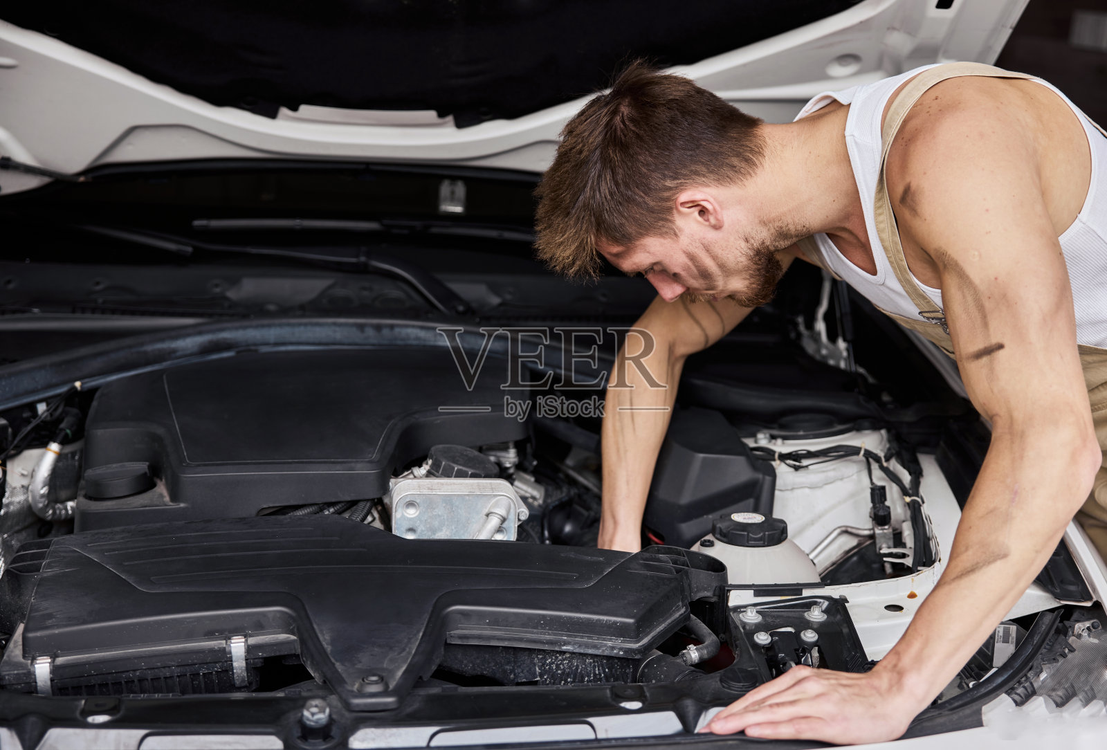 一个修理工在他的车库里工作的肖像。照片摄影图片