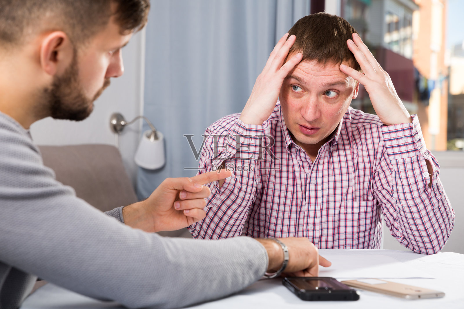 和朋友在家里桌子上焦急地看报纸的人照片摄影图片