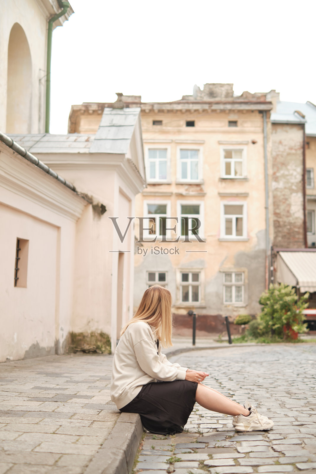 一位金发美女坐在舒适的城市街道上。周末去欧洲城市转转。休闲和冒险。在城市里度过快乐的早晨。去欧洲旅行，旅游。周末共鸣照片摄影图片