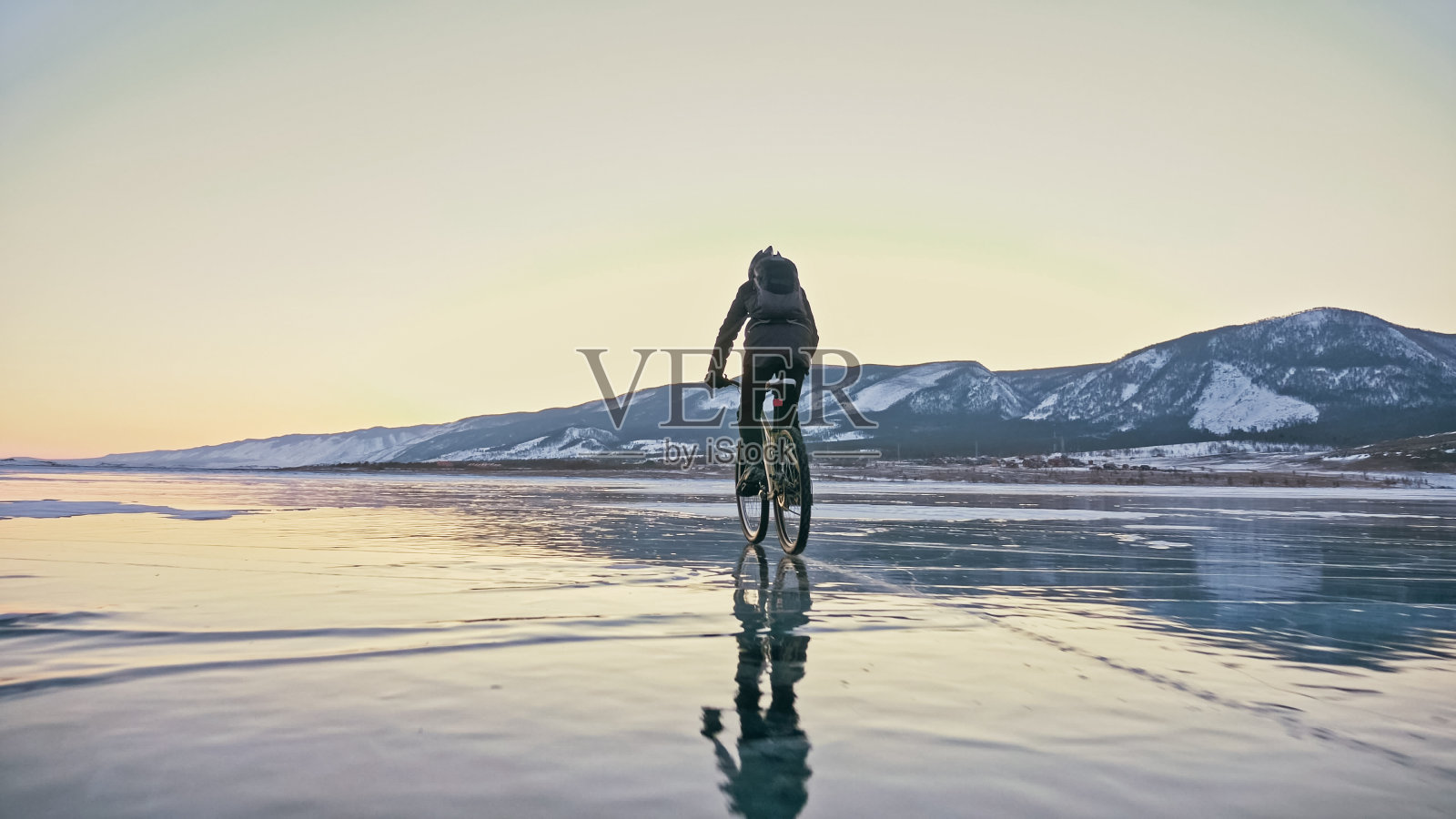 男人在冰上骑自行车。冻结的贝加尔湖的冰。三通照片摄影图片