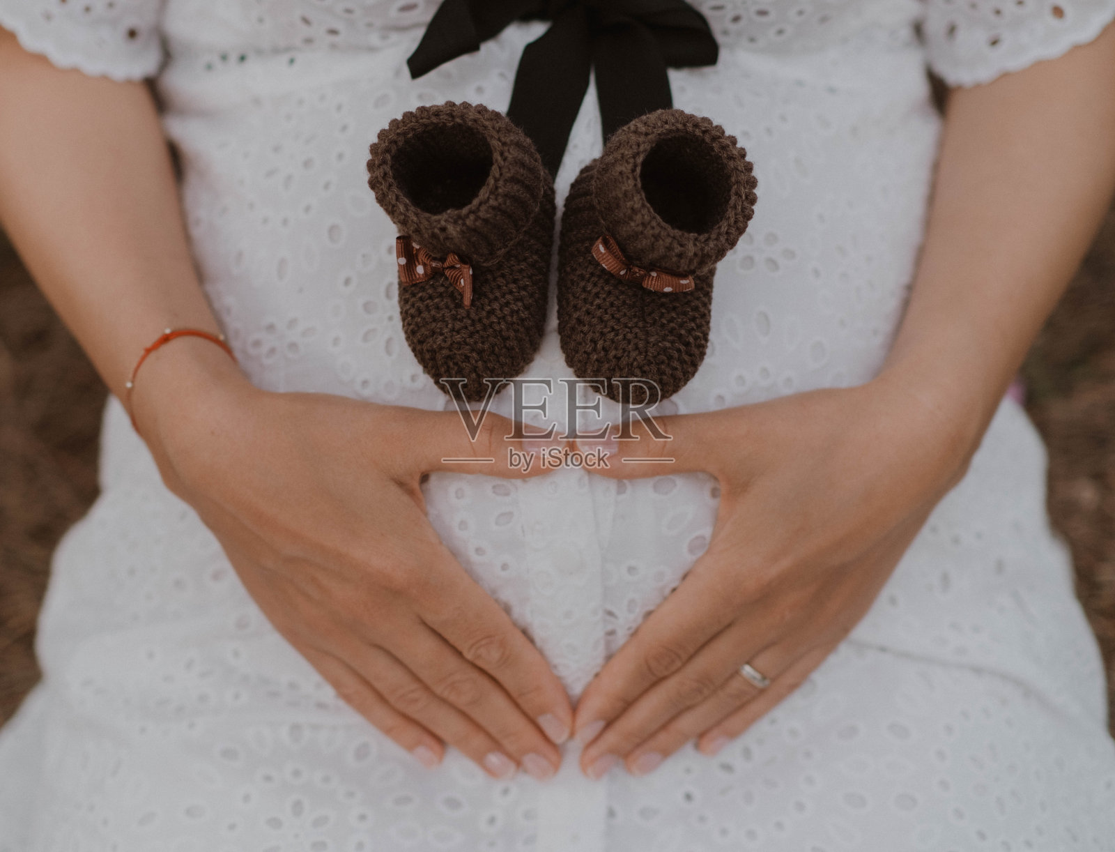 那位母亲正怀着她的孩子。小婴儿鞋。照片摄影图片