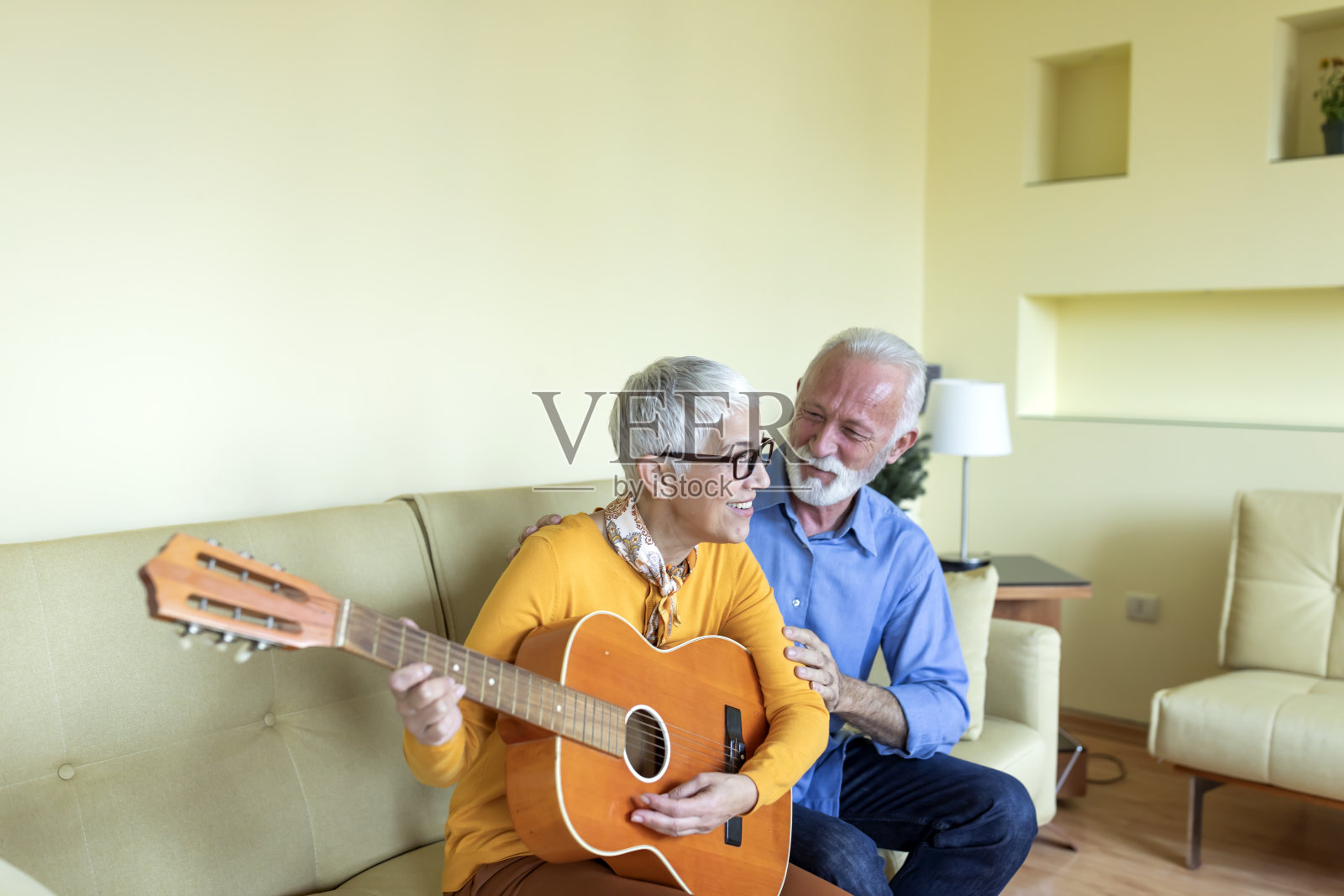 一位老年妇女很乐意弹吉他，向她的丈夫表达爱意。照片摄影图片