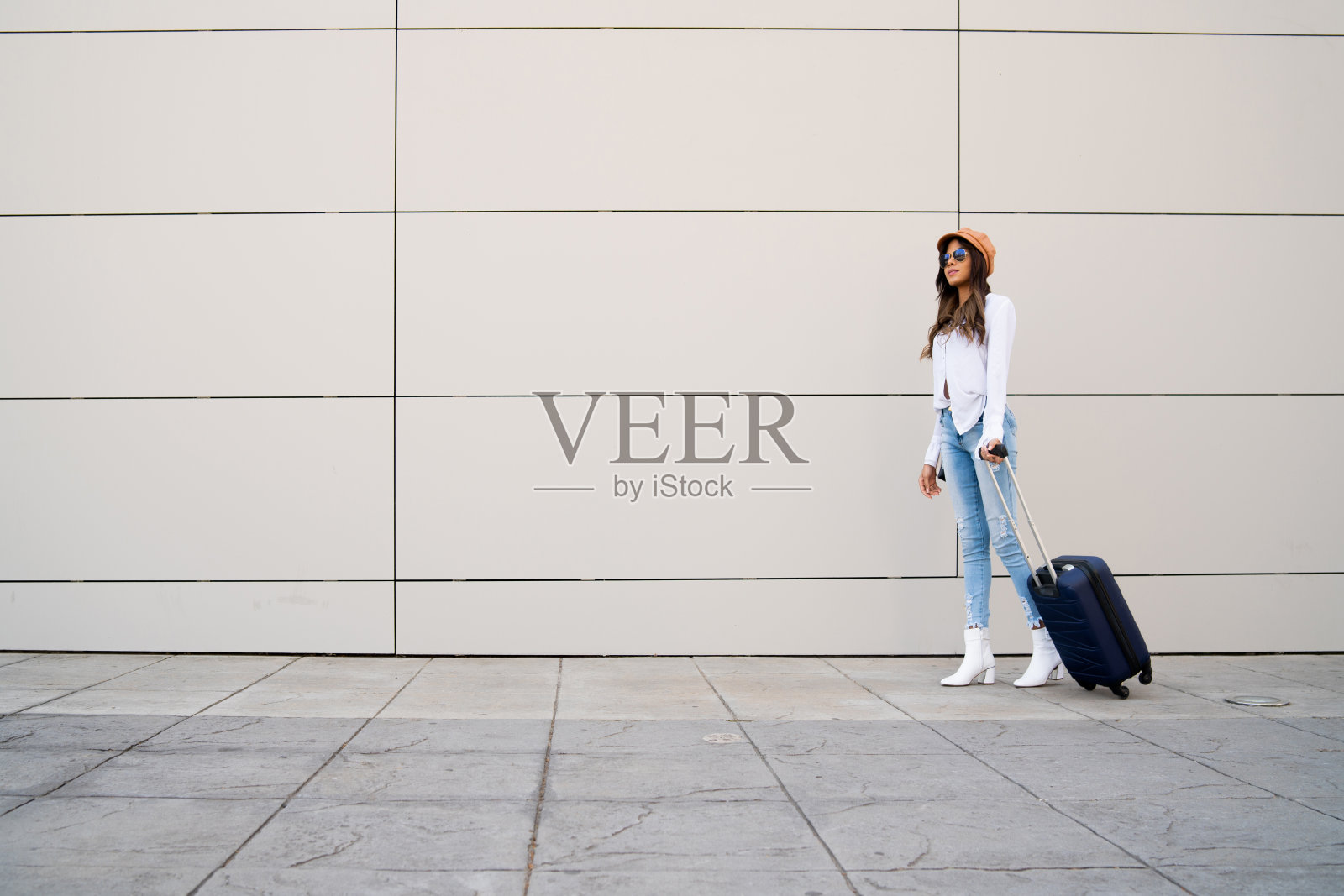 一个年轻女子提着一个手提箱在户外。照片摄影图片