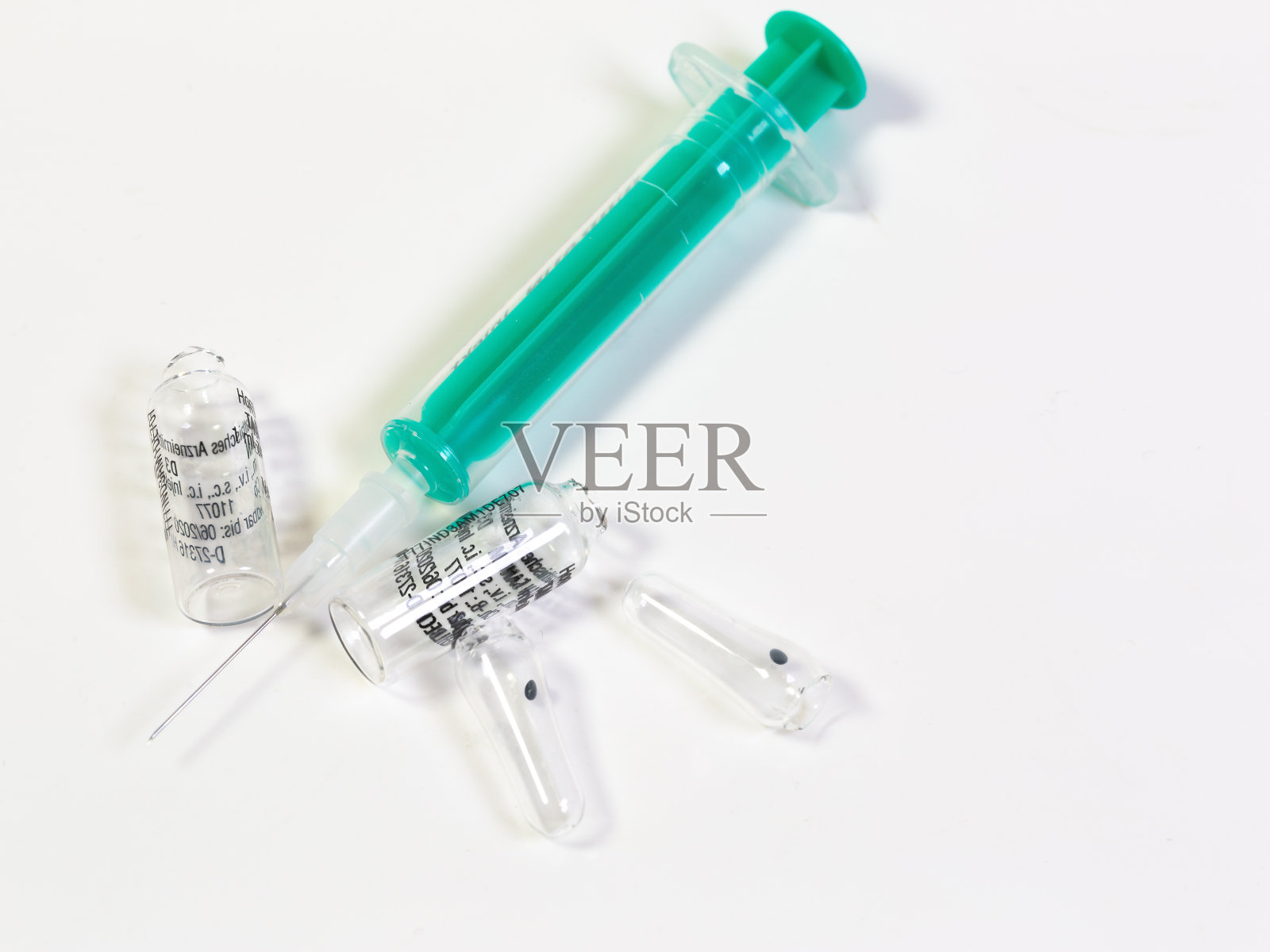白色背景上有一支注射器和两支断了的安瓿照片摄影图片