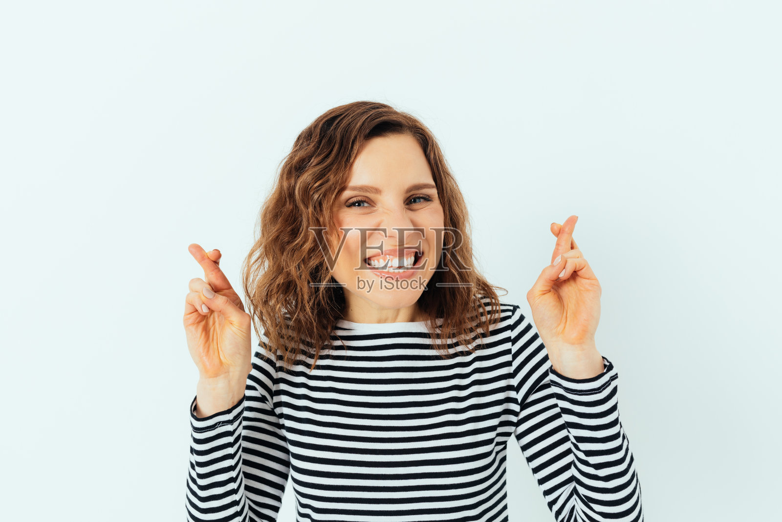 快乐又兴奋的年轻女子在交叉手指许愿照片摄影图片