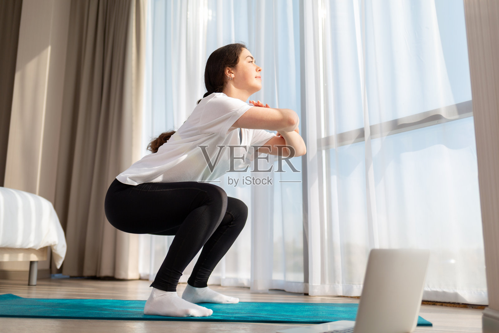 一个年轻苗条的女人穿着运动服在家里学习在线课程。底部视图。家庭在线培训的概念照片摄影图片