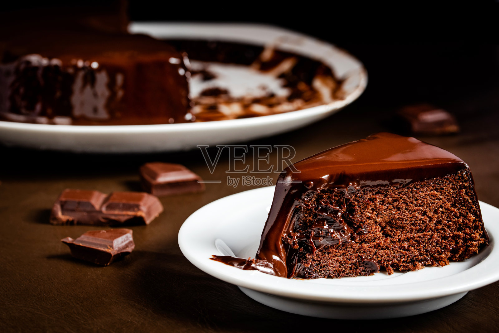 巧克力蛋糕切片放在桌子上的白色盘子里。照片摄影图片