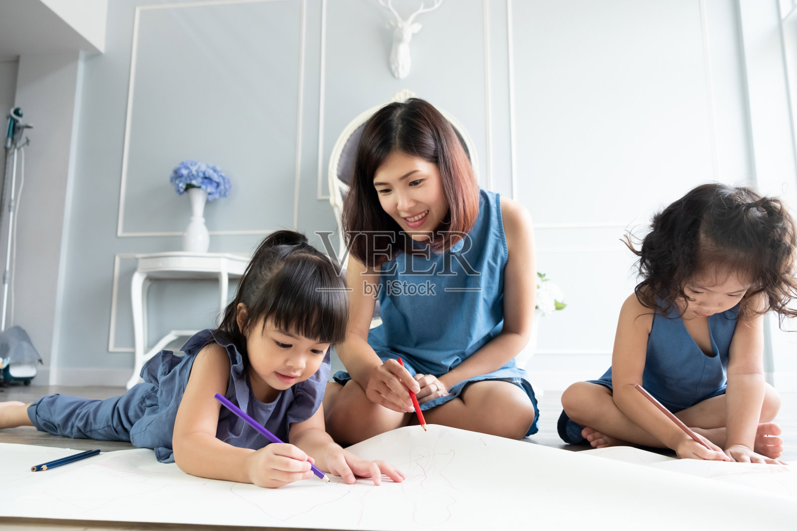 快乐的年轻母亲在家里教她的两个小女儿。孩子教育的概念。照片摄影图片