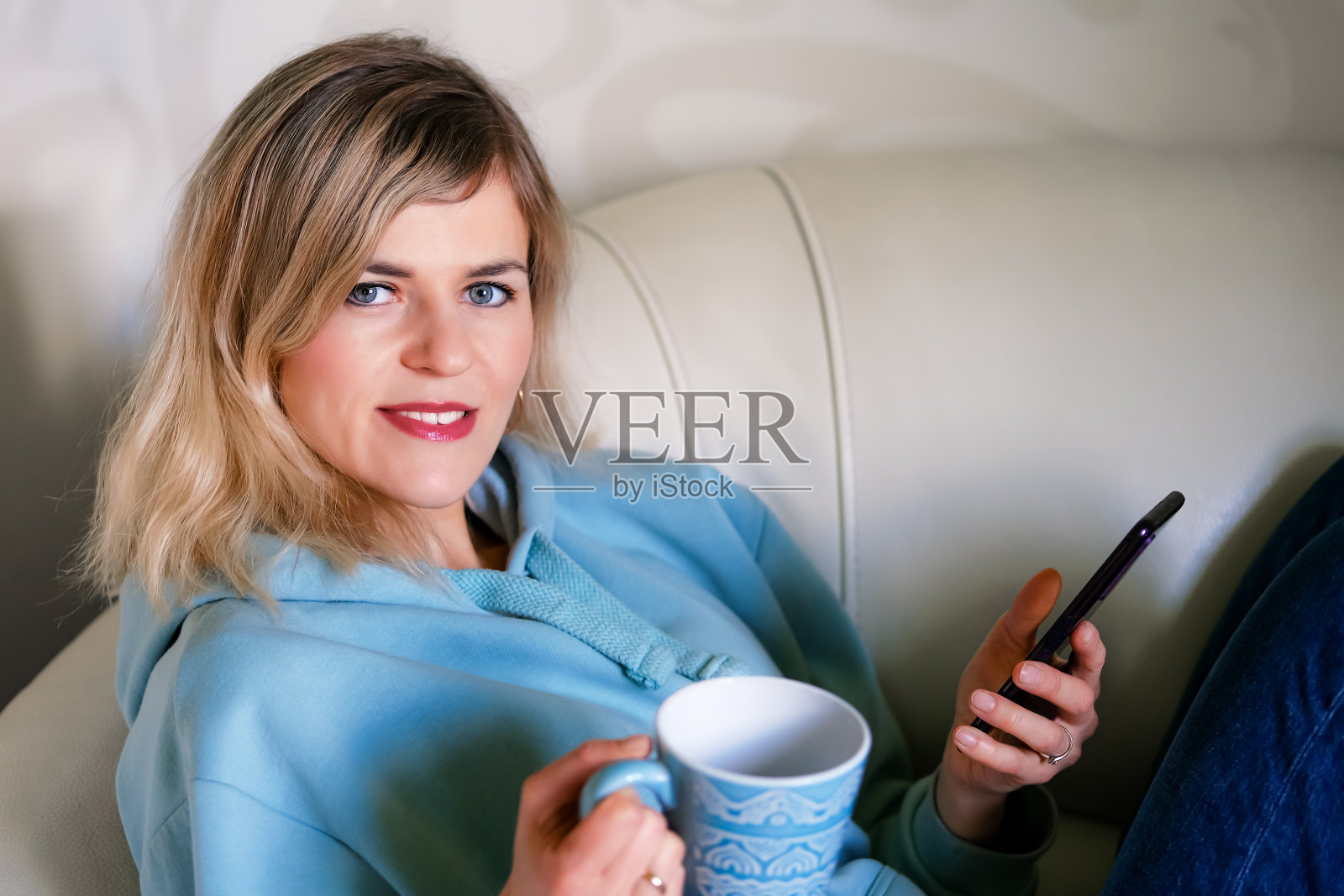 沙发上的女人拿着咖啡杯和手机照片摄影图片